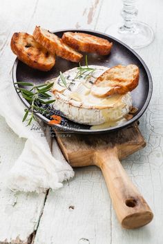 an open faced sandwich on a black plate next to some bread and wineglasses