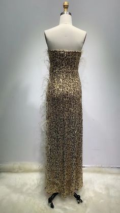 Introducing our handmade exquisite Luxury Gold Sequins Feather Gala Dress, a true embodiment of glamour and elegance. This sleeveless masterpiece is designed to make a statement at any special occasion. The off-the-shoulder sleeve style adds a touch of sophistication, highlighting your shoulders and neckline with grace. Crafted with meticulous attention to detail, this dress features a natural waistline that accentuates your curves, creating a flattering silhouette. The V-neckline adds a hint of allure, drawing attention to your décolletage. The chapel train gracefully trails behind you as you make a grand entrance, adding an extra touch of sophistication. With its floor-length design, this dress exudes timeless beauty. The fashion-forward element of a thigh-high slit adds a contemporary t Fitted Sleeveless Evening Dress With Feathers, Sleeveless Feathered Evening Dress For Party, Sleeveless Feathered Evening Dress For Gala, Sleeveless Feather Evening Dress For Party, Sleeveless Elegant Evening Dress With Feather Trim, Elegant Strapless Dress With Feather Trim, Formal Sleeveless Evening Dress With Feathers, Luxury Strapless Dress For Party Season, Luxury Gold Strapless Dress