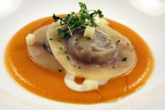 a white plate topped with dumplings covered in sauce and garnished with parsley