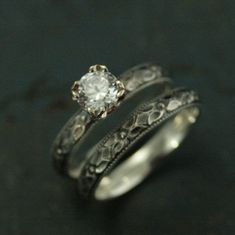 two wedding rings with an old - fashioned design and a round diamond in the center