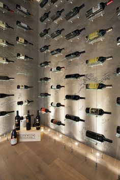 a room filled with lots of bottles of wine on the wall next to a wooden floor