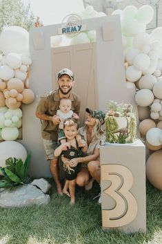 a man and woman with their two children in front of a birthday cake at an outdoor party