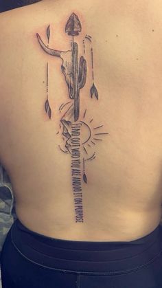 the back of a woman's upper body with an arrow and sun tattoo on it