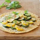 a tortilla with zucchini and spinach on a wooden cutting board