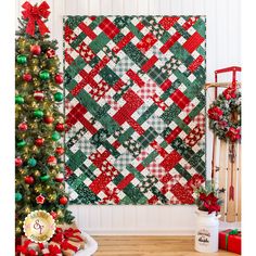 a christmas quilt hanging on the wall next to a tree with presents and ornaments around it