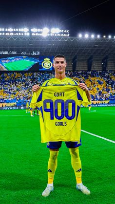 a soccer player holding up a yellow shirt in front of a stadium full of people