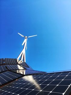 a wind turbine on top of a roof with solar panels and blue sky in the background