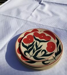 a red and black flowered plate sitting on top of a white cloth covered table