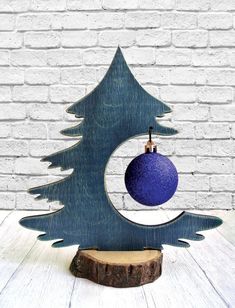 a wooden christmas tree with a blue ball hanging from it's center and an ornament in the middle