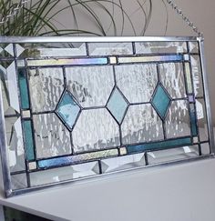 a stained glass window sitting on top of a white table next to a potted plant