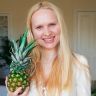 a woman holding a pineapple in front of her face and smiling at the camera