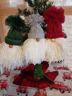 three knitted santa clause hats sitting on top of a christmas tablecloth covered table