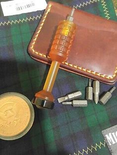 a hammer and some other items are on a table next to a coin, which has been placed in front of a leather wallet