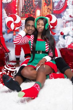 a man and woman sitting next to each other in front of a christmas tree with candy canes