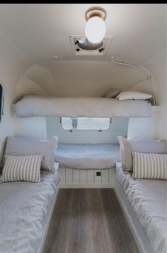 the inside of a camper with two beds and pillows