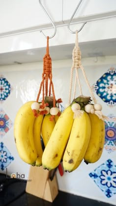 bunches of bananas hanging from hooks in a kitchen