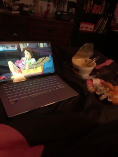 an open laptop computer sitting on top of a bed next to stuffed animals and toys