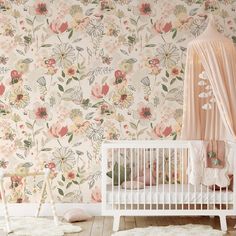 a white crib in front of a floral wallpaper