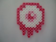 a pink and white wall hanging made out of legos with the letter o on it