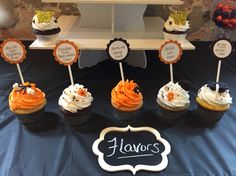 cupcakes with frosting and decorations are displayed on a table