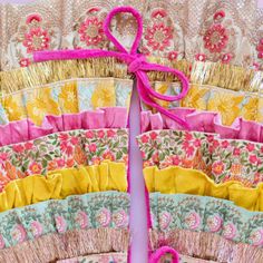 a close up of many different colored pieces of cloth with pink ribbon tied to it