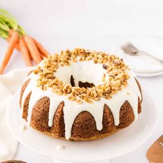 a bundt cake with white icing and chopped carrots next to it on a plate