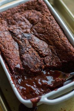 a close up of a cake in a pan with chocolate sauce on the side and a spoon