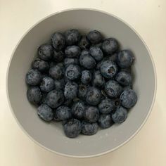 a white bowl filled with blueberries on top of a table