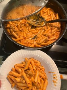 two plates filled with pasta next to a pot of food on top of a stove