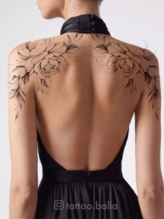 the back of a woman's dress with tattoos on her shoulder and neckline