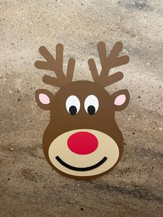 a cardboard reindeer head with eyes and nose cut out on the concrete floor, ready to be used as a decoration