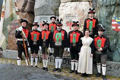 a group of people standing next to each other in front of a rock formation with flags