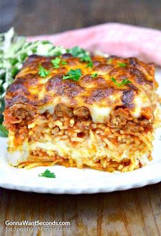 lasagna casserole on a white plate with green beans and parsley