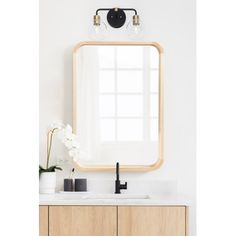 a bathroom vanity with a large mirror above it and a vase on the counter next to it