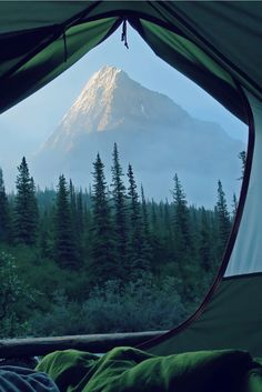 the view from inside a tent looking out at a mountain and trees in the distance