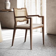 a wooden chair sitting in front of a table with a vase on top of it