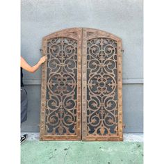 two wooden doors with intricate designs on the sides and one has a person standing next to it