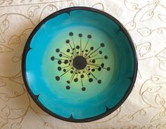 a blue bowl sitting on top of a table next to a white tablecloth with black dots