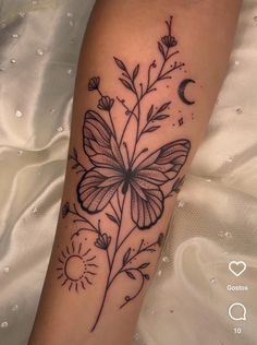 a black and white photo of a butterfly with flowers on it's arm, next to the moon