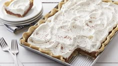 a pie sitting on top of a pan covered in frosting next to plates and utensils