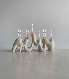 four white candles are lined up in the shape of elephants with long, slender legs