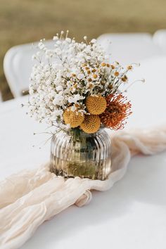 a vase filled with flowers sitting on top of a white tablecloth covered dining room table