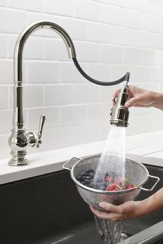 a woman is pouring water into a bowl with berries and blueberries in it on the kitchen sink