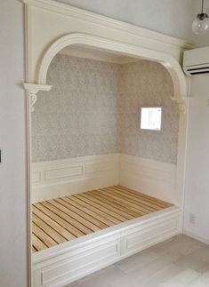 an empty room with a wooden bed in the middle and a window on the far wall