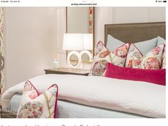 a bed with colorful pillows on top of it and a lamp next to the bed