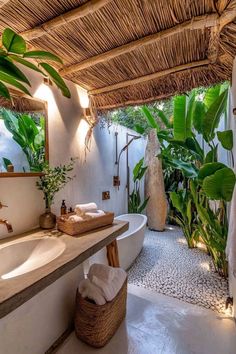 a bathroom with a tub, sink and large mirror in the center is surrounded by greenery