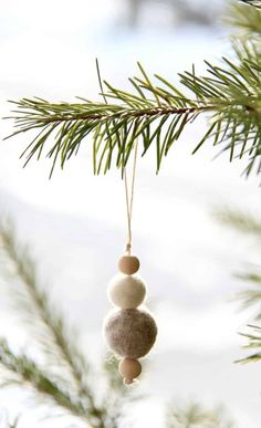 a christmas ornament hanging from a pine tree with snow on the ground in the background