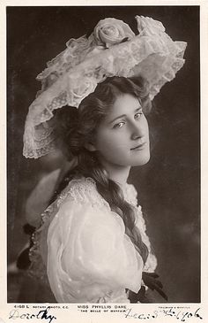 an old black and white photo of a woman wearing a hat with flowers on it