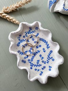 two wedding rings are placed in a blue and white flowered bowl on a table