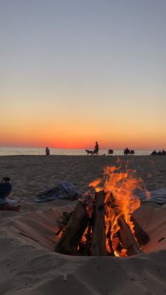 a fire pit on the beach with people in the background